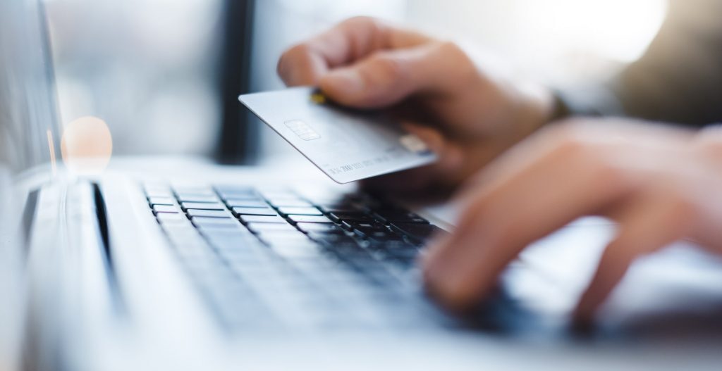 Online Casino Bonuses, Casino Bonus Offers in Canada Hands holding credit card over laptop keyboard.