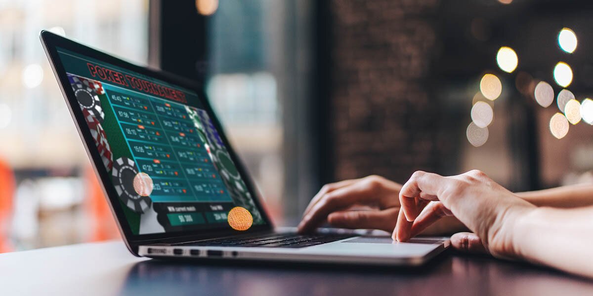 Hands using laptop with poker on the screen.