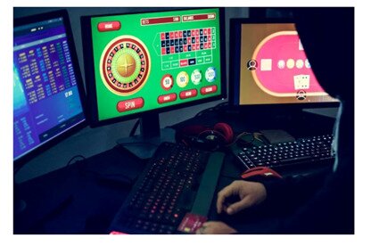 person sitting at computer screens gambling
