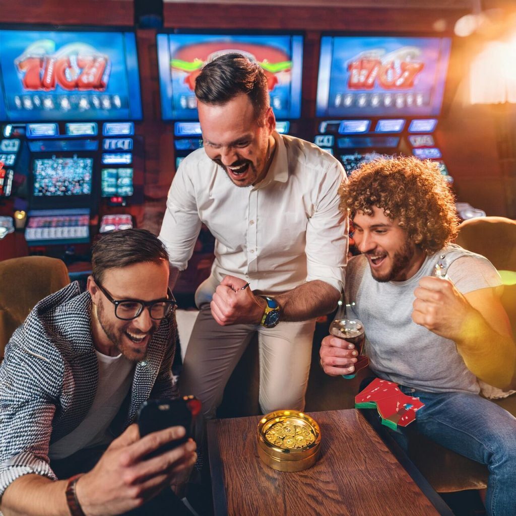 3 guys at the slots cheering at a cellphone