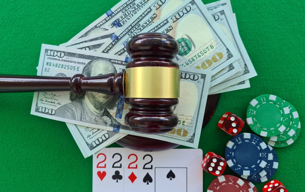 A casino table with a gravel and money, playing cards, and poker chips
