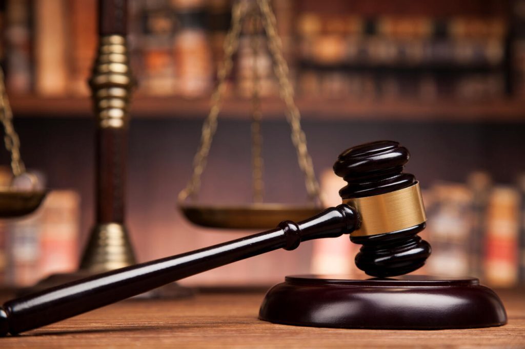 A gavel resting in front of the scales of justice.